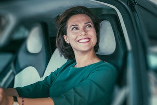 Zadowolona kobieta kupująca używany samochód, który jest ubezpieczony w Warcie 