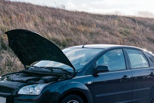 Mężczyzna wzywający pomoc po  uszkodzeniu jego czarnego samochodu ubezpieczonego w Warcie 