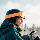 Kobieta w pomarańczowym kasku narciarskim symbolizująca ubezpieczenie turystyczne na wyjazd w góry 