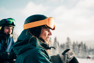 Kobieta w pomarańczowym kasku narciarskim symbolizująca ubezpieczenie turystyczne na wyjazd w góry 