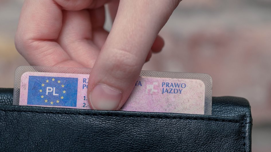 Zdjęcie dłoni mężczyzny wyciągającej prawo jazdy z portfela