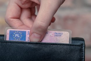 Zdjęcie dłoni mężczyzny wyciągającej prawo jazdy z portfela