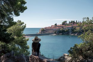 Kobieta siedzi nad wodą i obserwuje widok na Budvę