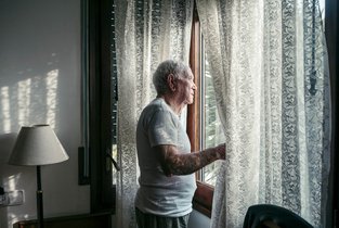 Starszy mężczyzna w białej koszulce przy oknie 
