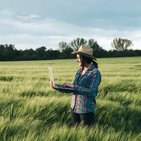 rolnik analizuje dane na komputerze stojąc w polu