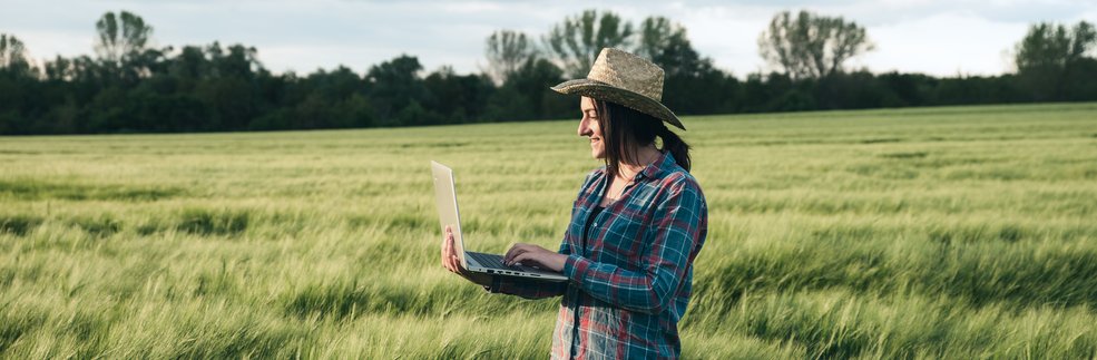 rolnik analizuje dane na komputerze stojąc w polu