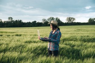 rolnik analizuje dane na komputerze stojąc w polu