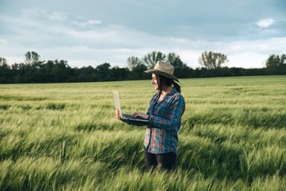 rolnik analizuje dane na komputerze stojąc w polu