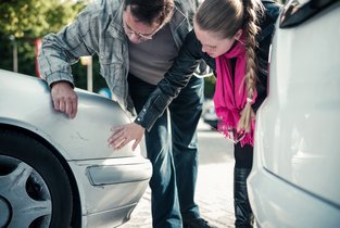 Kobieta i mężczyzna oglądają zarysowania samochodu po stłuczce.