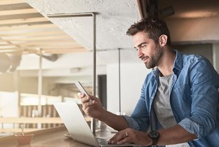 Mężczyzna używający telefonu oraz laptopa