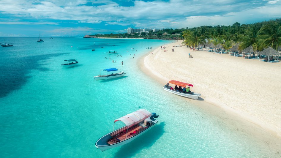 Łódki i turyści relaksujący się na plaży Zanzibaru