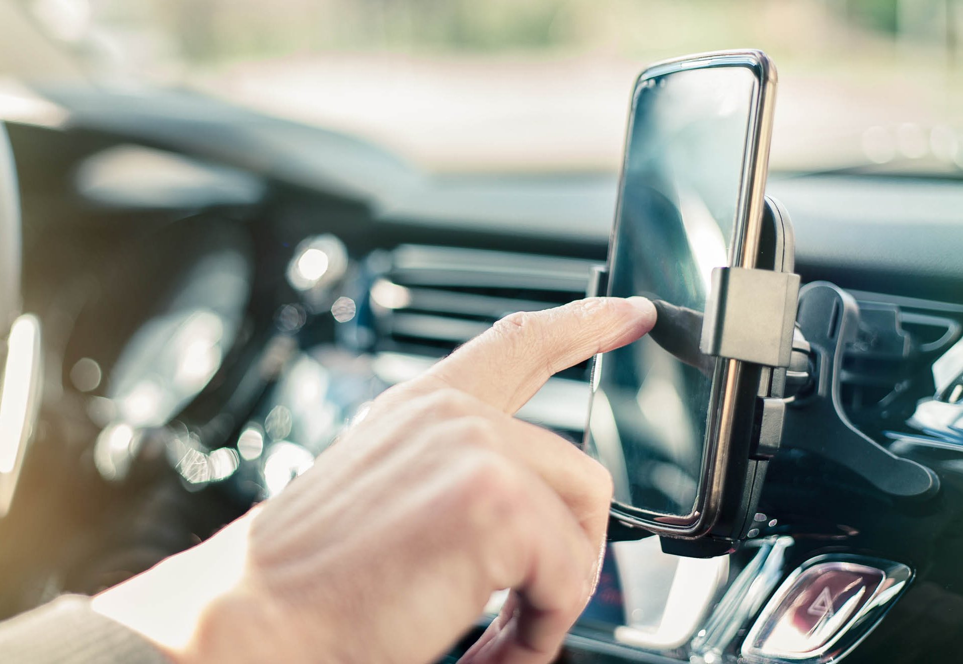 Mężczyzna siedzi w samochodzie i w telefonie sprawdza ubezpieczenie OC Mężczyzna sprawdzający informacje w telefonie