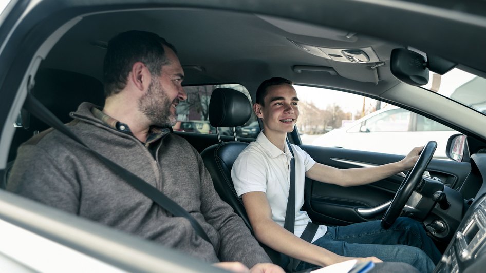 Przebieg egzaminu na prawo jazdy - młody mężczyzna prowadzi auto i rozmawia z egzaminatorem
