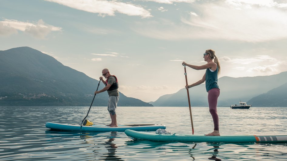 Dwoje ludzi płynących na deskach Stand Up Paddle po norweskim fiordzie