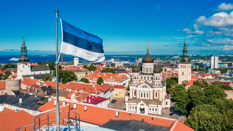 Flaga Estonii powiewająca na tle jej stolicy - Tallinu