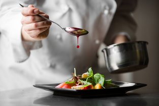 Szef kuchni przygotowywuje danie w swojej restauracji, która jest ubezpieczona w Warcie 