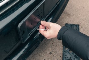 Mężczyzna montuje mocowanie tablicy rejestracyjnej