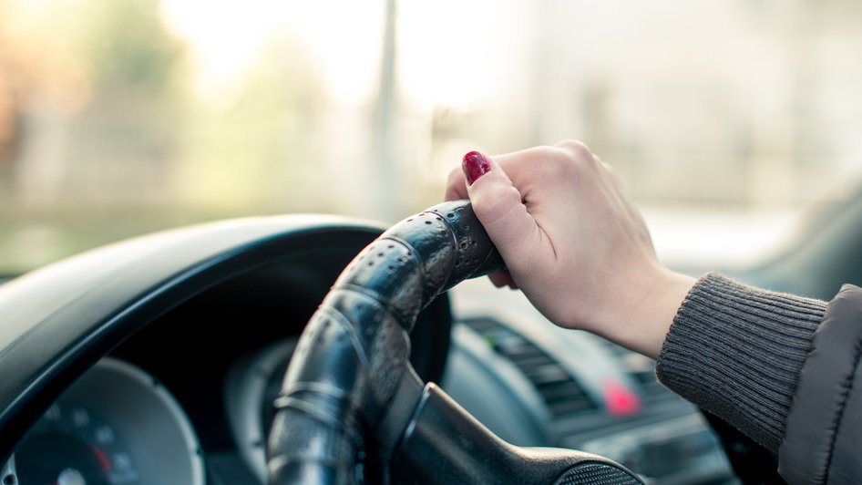 Kobieta siedzi w samochodzie na parkingu i zorientowała się, że nieznany sprawca uszkodził jej auto.