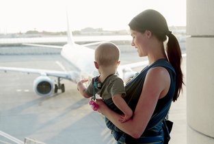 Mama czeka z małym dzieckiem na lotnisku i pokazuje mu samolot.