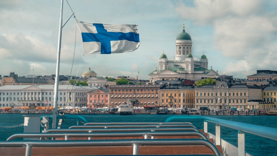 Flaga Finlandii na łódce, a w tle widok na stolicę - Helsinki
