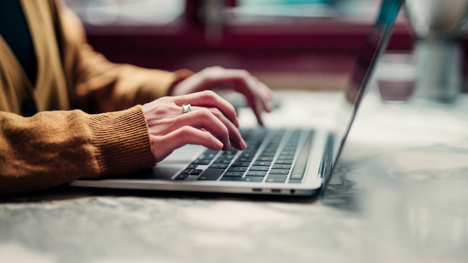 Mężczyzna w żółtej koszuli pisze na laptopie 