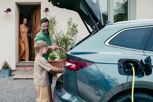 Tata z synem pakują rzeczy do bagażnika w trakcie ładowania hybrydy plug-in