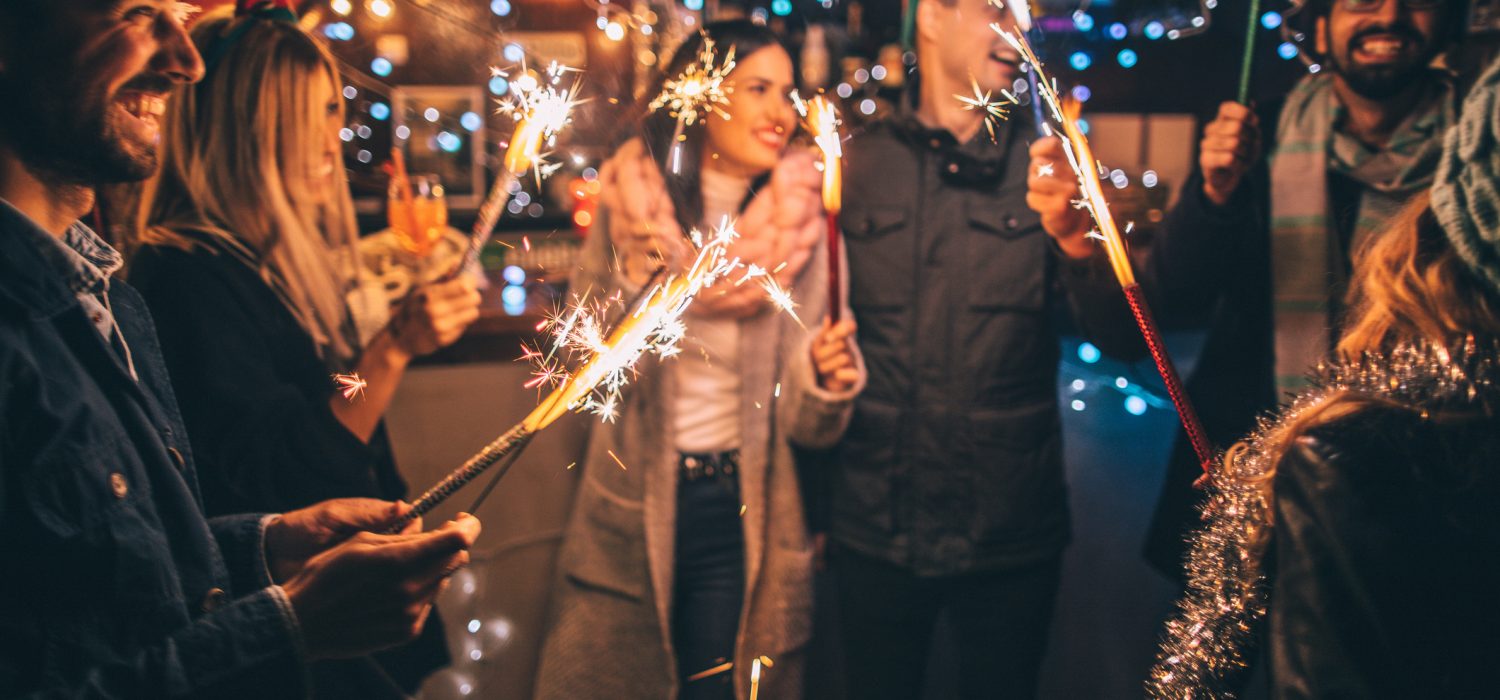 Grupa znajomych trzymająca zimne ognie świętująca sukces lub rozpoczęcie Nowego Roku