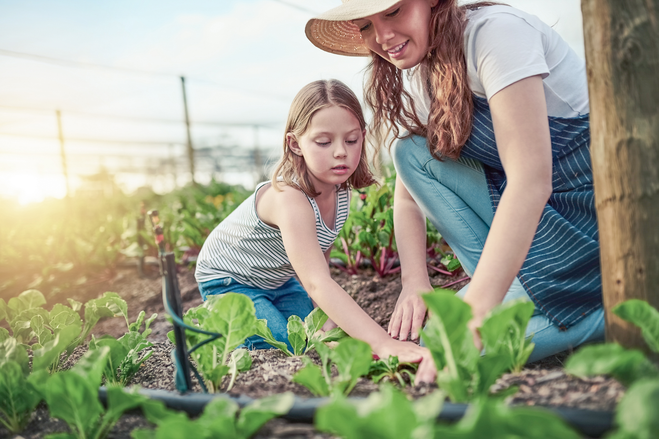 Jak postępować z raną zabrudzoną ziemią? Mama i córka pracują spokojnie w ogrodzie, ponieważ wiedzą, jak postępować z raną zabrudzoną ziemią.