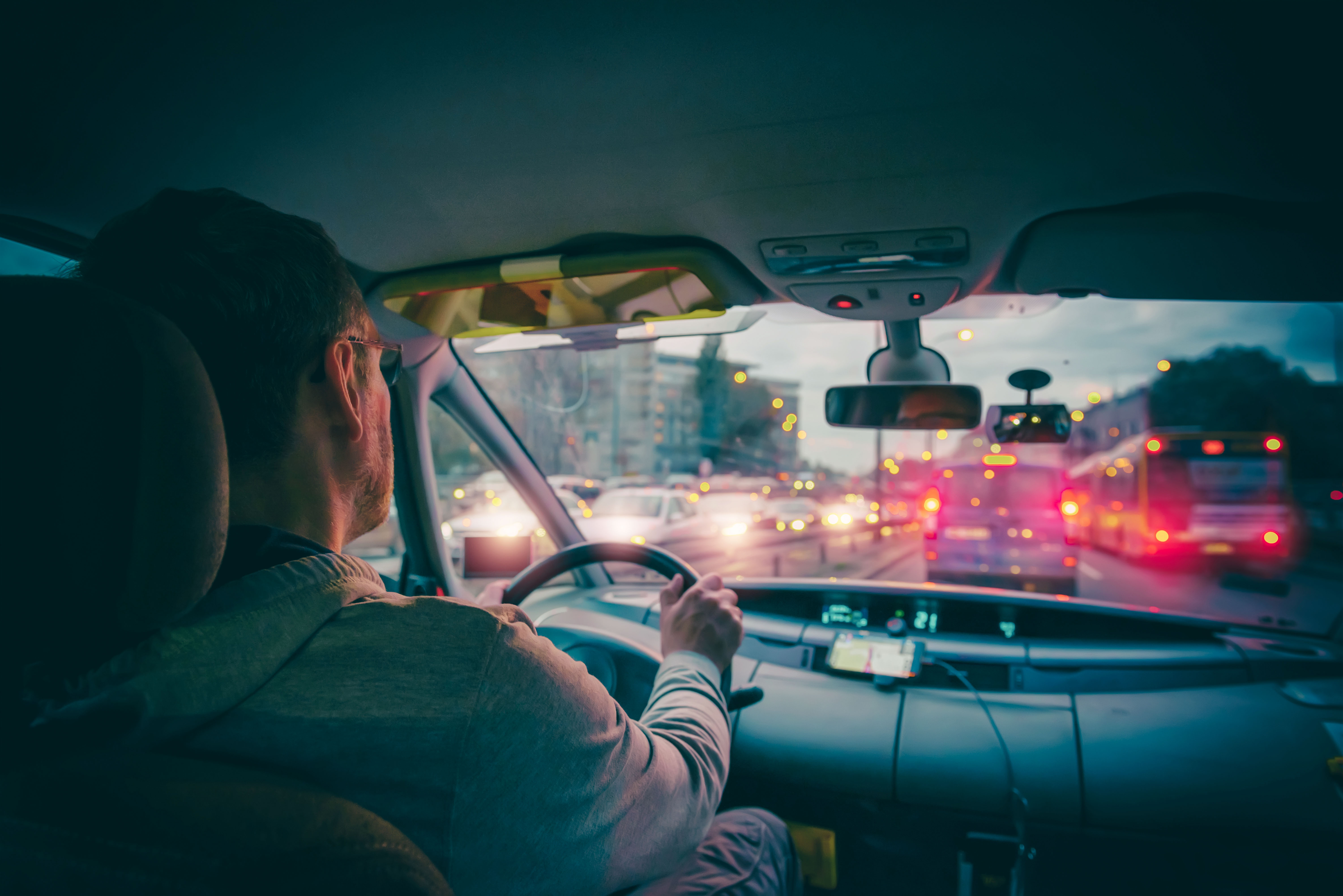 Mężczyzna jedzie samochodem wśród innych kierowców - na drodze jest korek.