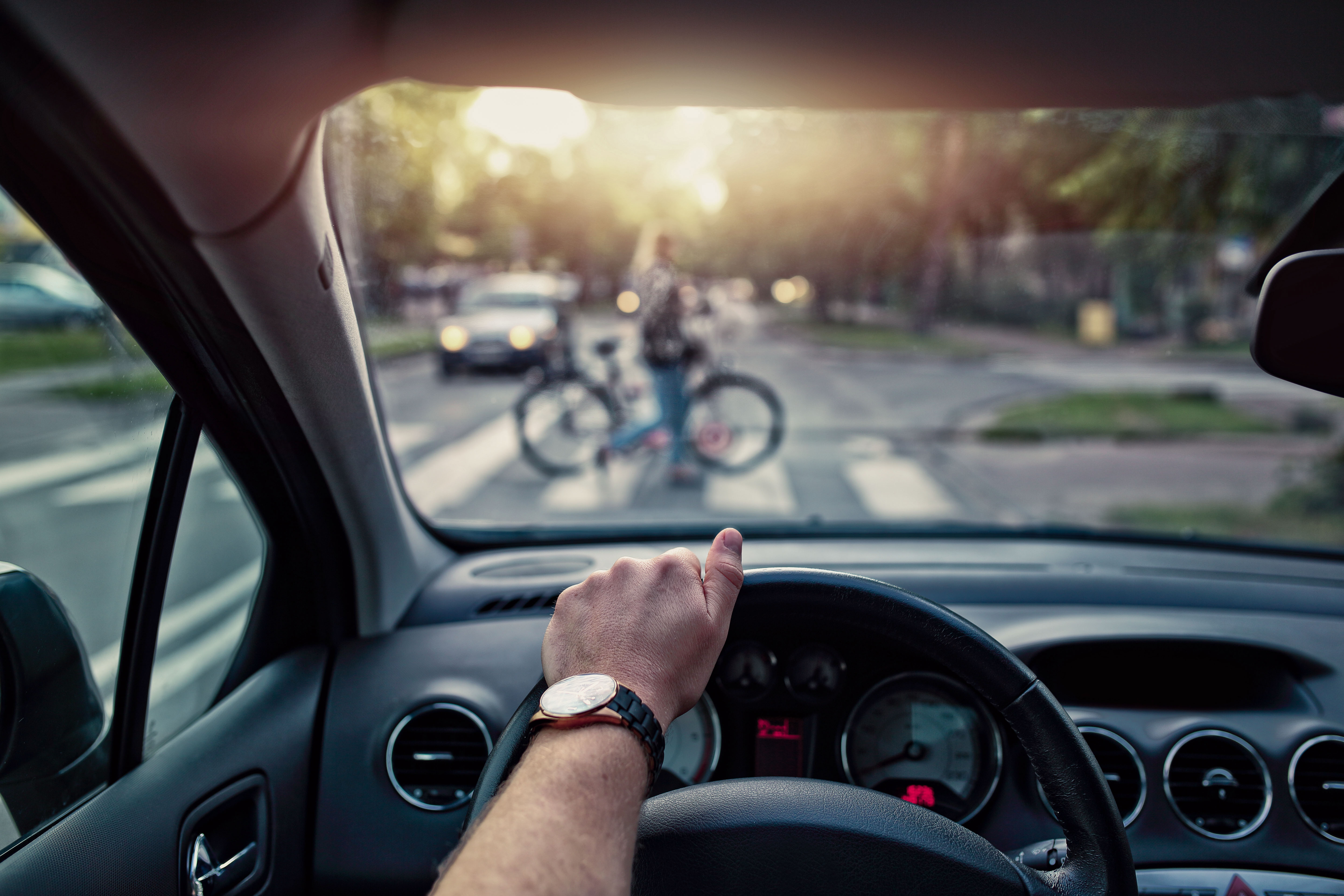 Kierowca zatrzymuje się przed przejściem dla pieszych i przepuszcza osobę prowadzącą rower.