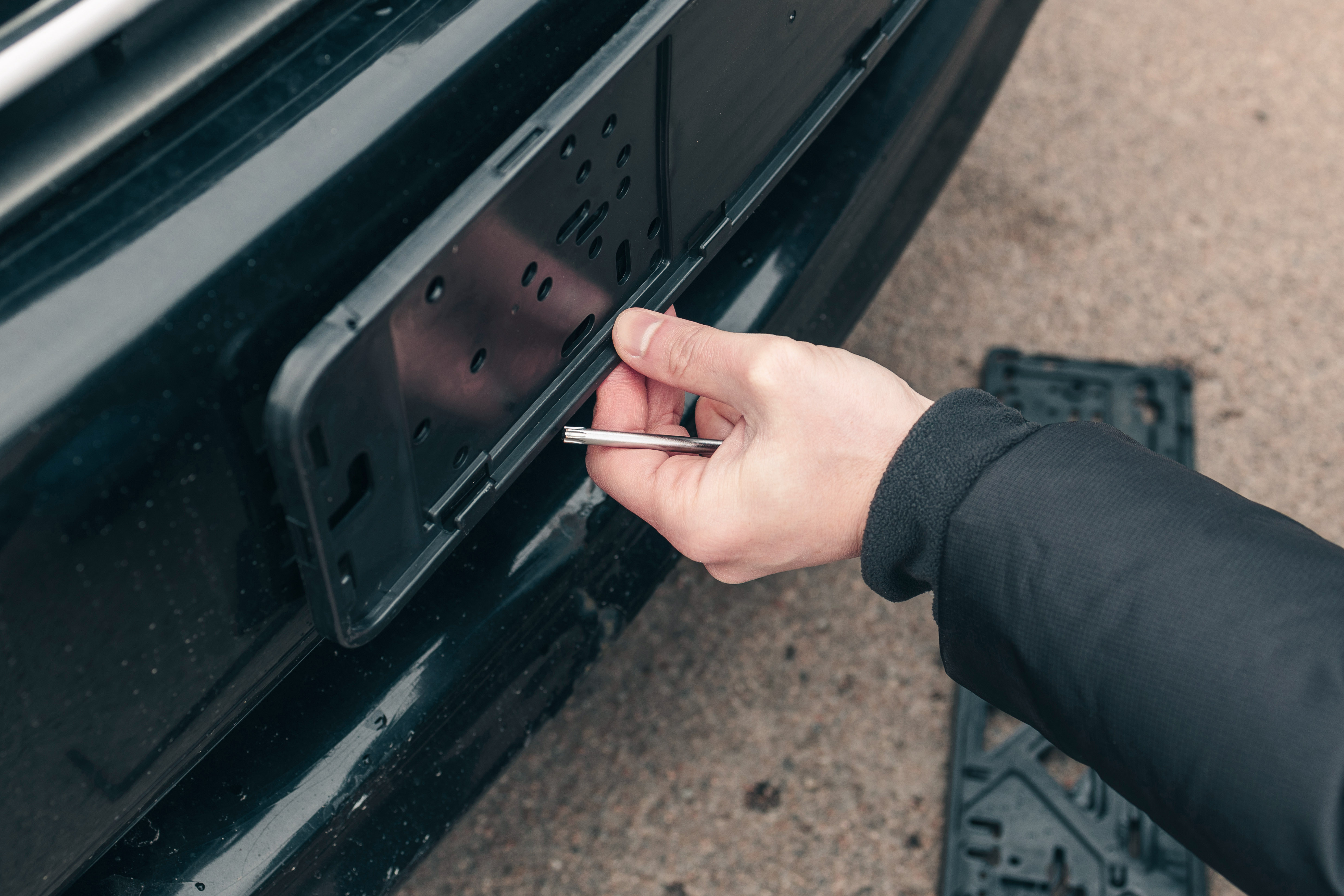 Mężczyzna montuje mocowanie tablicy rejestracyjnej