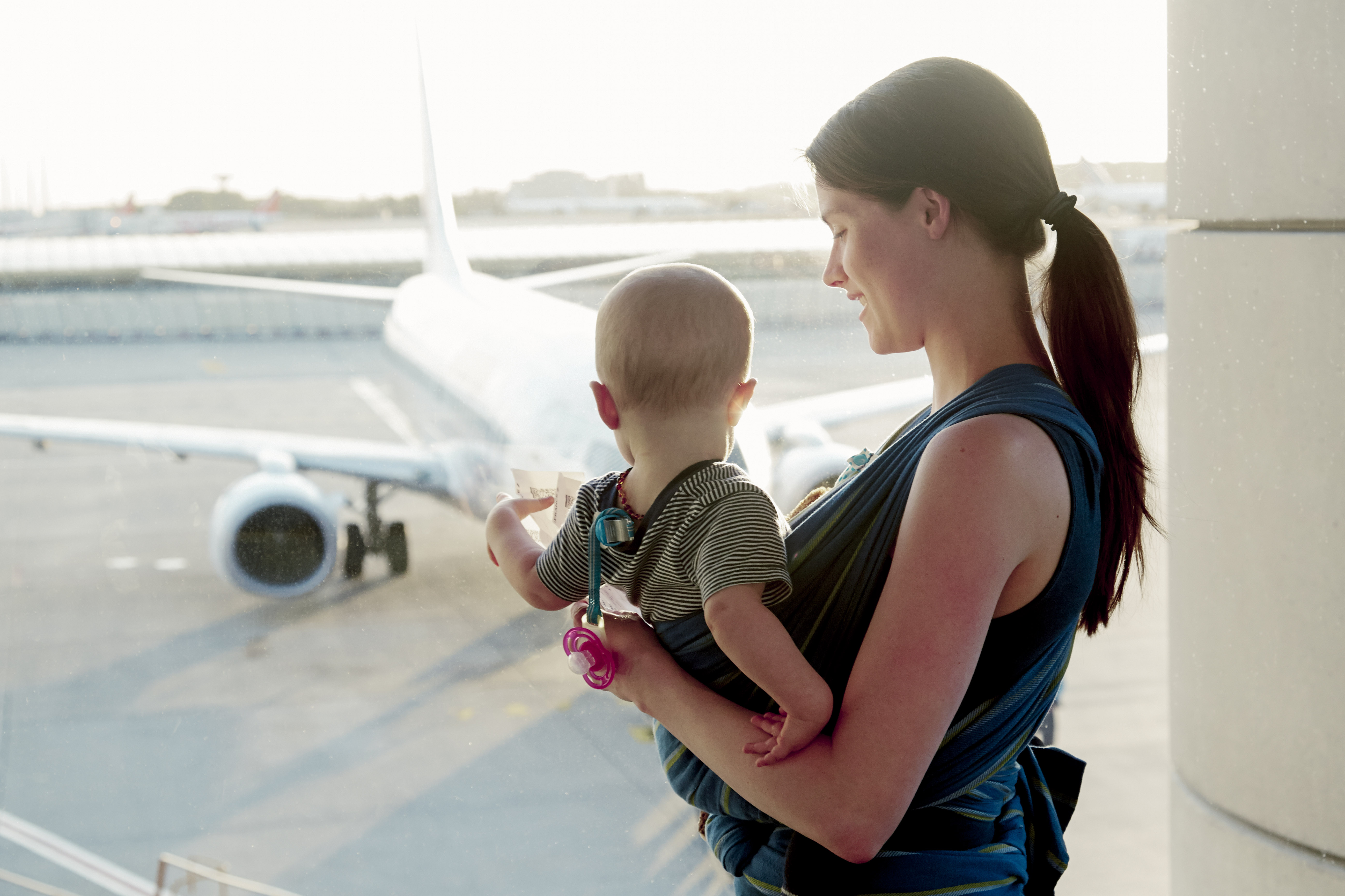 Mama czeka z małym dzieckiem na lotnisku i pokazuje mu samolot.